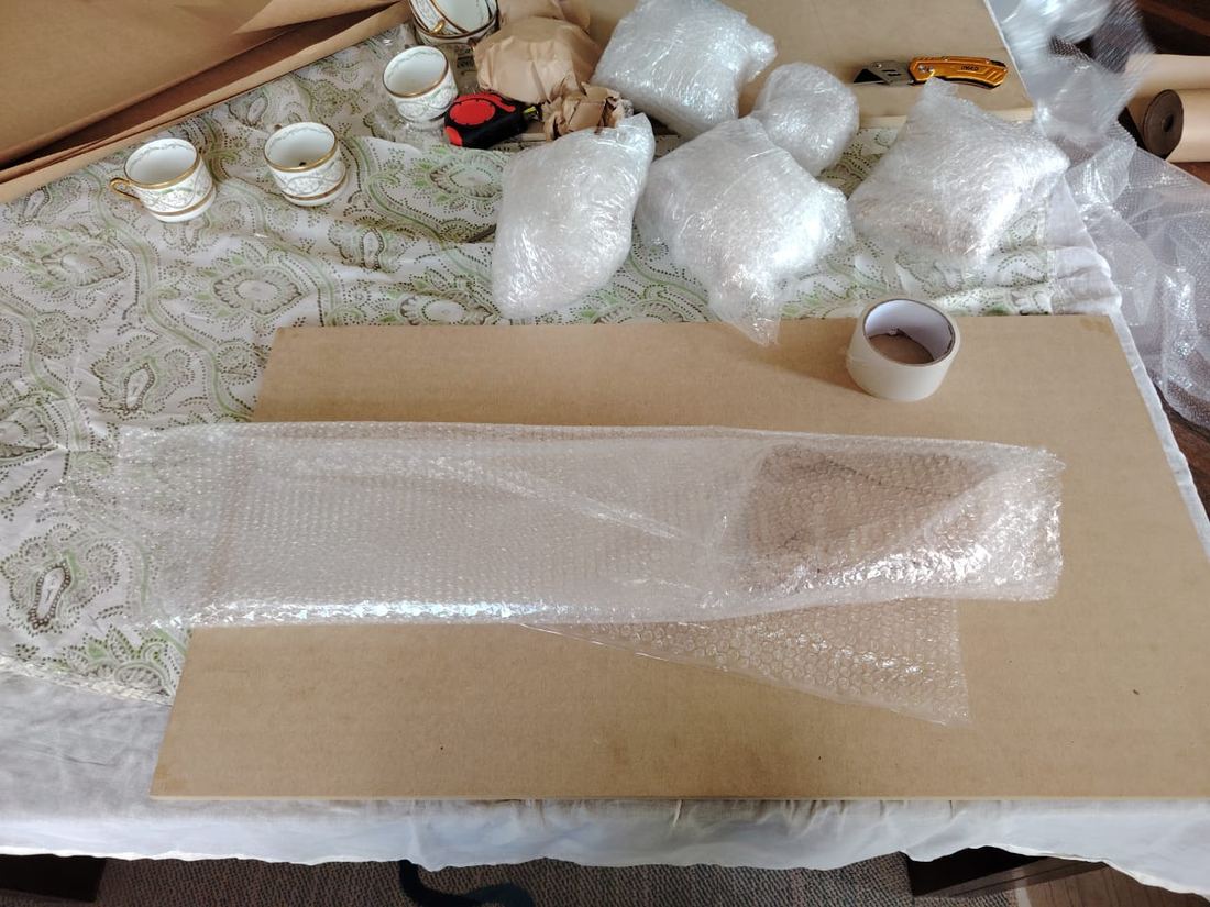 Pieza larga envuelta en plástico de burbuja sobre una mesa de trabajo