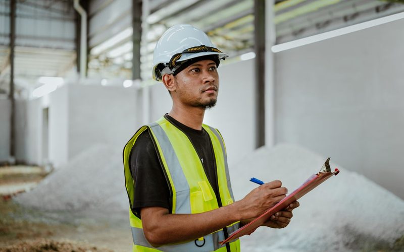 Técnico con casco anotando una evaluación en su carpeta